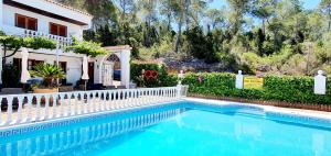 a swimming pool in front of a house with a white fence at Granada Apartments Familiar Deluxe in Portinatx
