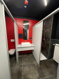 a bathroom with a sink and a toilet and red walls at Hotello Hostel in Trieste