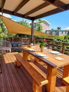 una mesa de picnic de madera en una terraza con sombrilla en L'embrun de jasmin en Beaumont