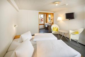 a room with two beds and a table and chairs at Hirschen Guesthouse - Village Hotel in Wildhaus