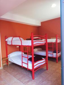 trzy czerwone łóżka piętrowe w pokoju ze ścianą w obiekcie O Encontro w mieście Fisterra +37 zdjęć