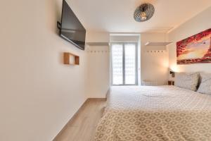 a bedroom with a bed and a television on the wall at Studio Le Rosier - Paris Gare du Nord en 15 min - in Deuil-la-Barre