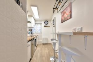 a kitchen with white walls and a counter and stool at Studio Le Rosier - Paris Gare du Nord en 15 min - in Deuil-la-Barre