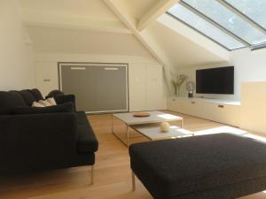 a living room with a black couch and a tv at Les Ecuries - Triplex contemporain avec jardin in Avignon