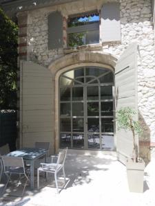 um pátio com uma mesa e cadeiras em frente a um edifício em Les Ecuries - Triplex contemporain avec jardin em Avignon