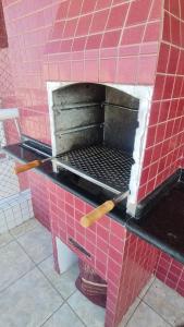 a red brick oven with two wooden utensils at Apartamento De Alto Padrão - Ocian in Praia Grande