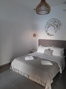 a white bedroom with a large bed and a chandelier at studios FLORA in naoussa paros in Naousa