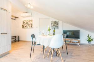 a white dining room with a table and chairs at Apartment Egon in Malinska