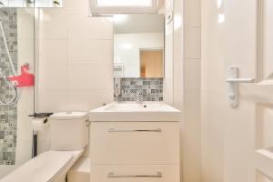 La salle de bains blanche est pourvue de toilettes et d'un lavabo. dans l'établissement L'Olivier - Paris Gare du Nord en 15 min -, à Deuil-la-Barre