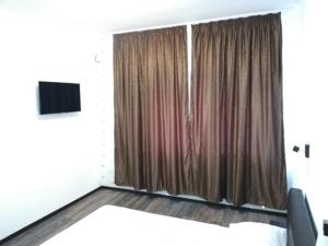 a bedroom with two beds and a window with curtains at Red House in Orşova