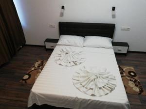 a bedroom with a bed with white sheets and shoes at Red House in Orşova
