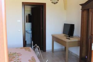 1 dormitorio con escritorio, TV y cama en Masseria Cricelli en Lizzanello