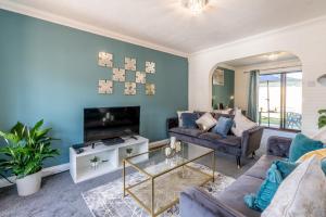 a living room with a couch and a tv at MK City Center House, perfect for FAMILIES, GROUPS, free parking, Sky TV, Desk space managed by CHIQUE PROPERTIES LTD in Milton Keynes