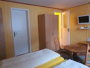 Schlafzimmer mit einem Bett, einem Tisch und einer Tür in der Unterkunft Hotel Klein Matterhorn in Randa