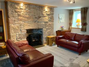 a living room with couches and a stone fireplace at No 10 The Cottage in Inverness