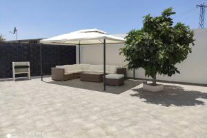 Apartamentos NayDa Gran casa con piscina في ماردة: فناء فيه مظلة بيضاء وشجرة