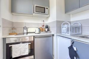 uma cozinha com um fogão e um micro-ondas em L'Elysée - Easy check-in - Arrivée autonome - Place parking privative - T2 suréquipé - Wifi - Netflix em Courcouronnes