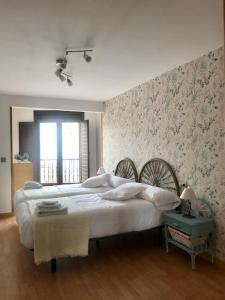 1 dormitorio con 1 cama blanca grande y papel pintado con motivos florales en Apartamento entero el Puente, en Cangas de Onís
