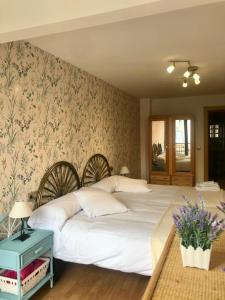 1 dormitorio con 1 cama blanca grande y papel pintado con motivos florales en Apartamento entero el Puente, en Cangas de Onís