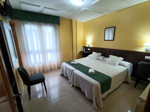 a hotel room with a bed and a chair at Hotel Casa Benilde in Palas de Rei 