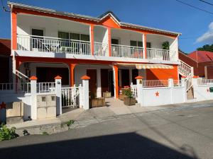 una casa naranja y blanca con una valla blanca en Les Lianes De Mysore, en Deshaies