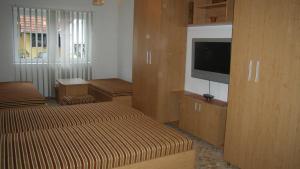 a living room with two beds and a flat screen tv at Pálma Apartmanház Harkány in Harkány