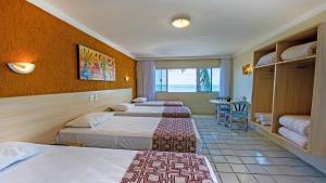 a hotel room with three beds and a table at Hotel Costeiro in Olinda