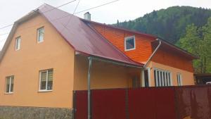 a house with an orange roof and a red fence at Садиба У Галина та Йосипа in Ustʼ-Chorna