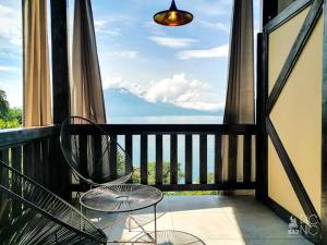 a balcony with two chairs and a view of the ocean at EL PICNIC ATITLÁN in Tzununá