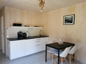 cocina con mesa, armarios blancos, mesa y sillas en Domek Morski en Swarzewo