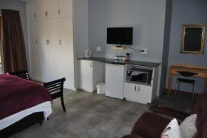 Schlafzimmer mit einem Bett und einem Schreibtisch mit einem TV in der Unterkunft 14 Cluster Cottages in George