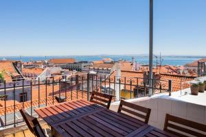 a balcony with a table and chairs on top of a city at Amazing Rooftop Terrace With River And Historic City View 4 Bedrooms 4 bathrooms AC 19th Century Building Chiado in Lisbon