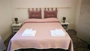 a bedroom with a pink bed with two towels on it at Visitponza - La casa di Eolo in Ponza