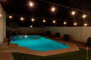 a swimming pool at night with lights on a fence at Game Room and Pool Spacious Queen Creek Home! in Queen Creek