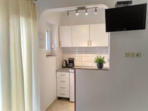 a kitchen with white cabinets and a counter top at Apartments Cizmesija in Baška