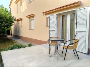 a patio with two chairs and a glass table at Apartments Cizmesija in Baška