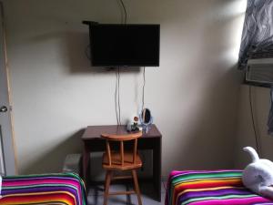 a room with a desk and a chair and a television at Hotel Antiguo in Antiguo Cuscatlán