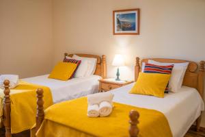 two beds in a room with yellow sheets and towels at Casa da Tia Clementina in Santana