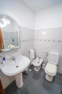 W łazience znajduje się umywalka, toaleta i lustro. w obiekcie Casa da Tia Clementina w mieście Santana