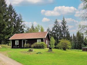 una pequeña casa en un campo de hierba al lado de una carretera en Two-Bedroom Holiday home in Åsarp 3, en Åsarp