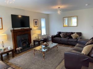 uma sala de estar com um sofá e uma televisão em The Grange, Portrush Sleeps 13 6 bedrooms em Portrush