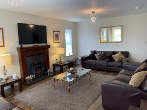 ein Wohnzimmer mit Sofa und Fernseher in der Unterkunft Luxury Portrush Holiday Homes - The Grange, Portrush Sleeps 13 - 6 bedrooms in Portrush