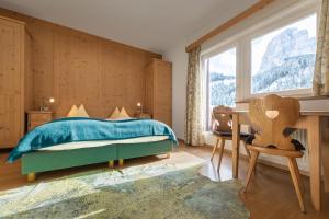 Schlafzimmer mit einem Bett, einem Schreibtisch und einem Fenster in der Unterkunft Apartments Heritage House Margherita in St. Christina in Gröden
