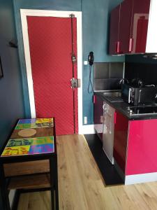 eine Küche mit einer roten Tür und einem Tisch in einem Zimmer in der Unterkunft Le Central Vittel 206 in Vittel
