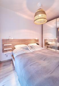 a bedroom with a large bed and a chandelier at LAGUNA Apartament Polanica Residence 29 in Polanica-Zdrój