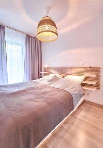 a bedroom with a large bed and a chandelier at LAGUNA Apartament Polanica Residence 29 in Polanica-Zdrój