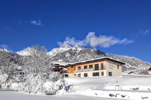 a building in the snow with a mountain in the background at Naturparkferienwohnungen Wolf in Hofen