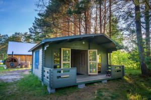 une petite maison verte avec une terrasse couverte dans l'établissement Metsaääre Accommodation, à Uulu