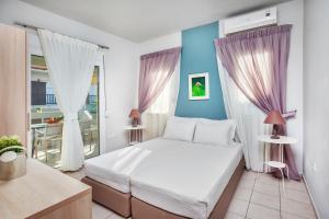 a bedroom with a white bed and purple curtains at Armyra studios in Pefkochori