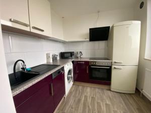 cocina con armarios morados y nevera blanca en Modernes Apartment Duisburg Homberg, en Duisburg